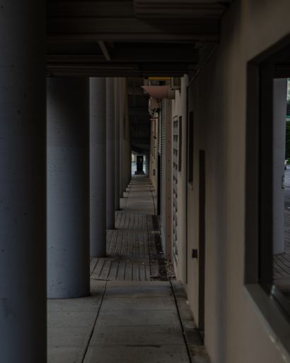 A modern urban scene featuring a sidewalk with pillars and a street light in front of a building with multiple windows