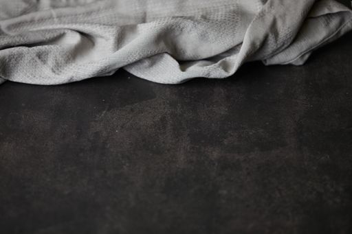 A horizontal shot of a plain gray cloth laid on a dark brown surface