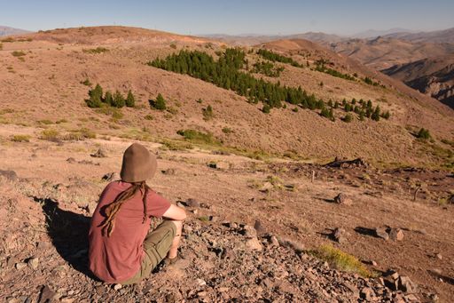A closeup of the young man sitting against the background of vale and mountains. Argentina.
