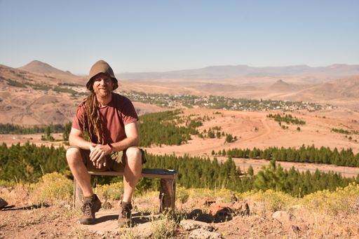 A closeup of the young man sitting against the background of vale and mountains. Argentina.