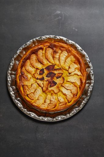 A vertical picture of an apple cake on a grey surface