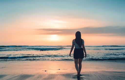 A picture of a female against a mesmerizing orange sunset and ocean