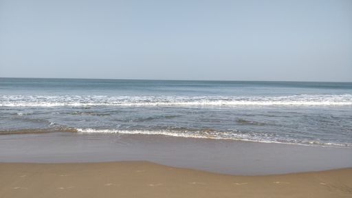A beautiful view of a beach with waves under the clear sky