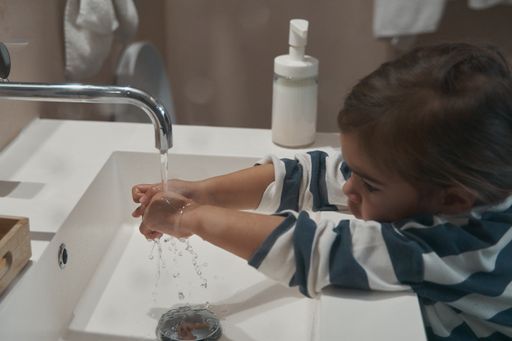 A Caucasian little girl washing hands in the bathroom