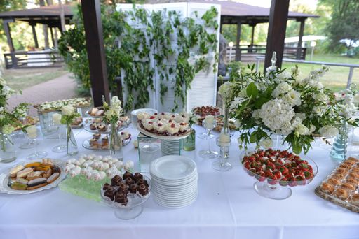 A high angle shot of dessert on the table decorated with bouquets under the sunlight - wedding concept