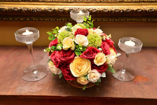 A high angle shot of a bouquet of roses in a basket on the table with candles under the lights