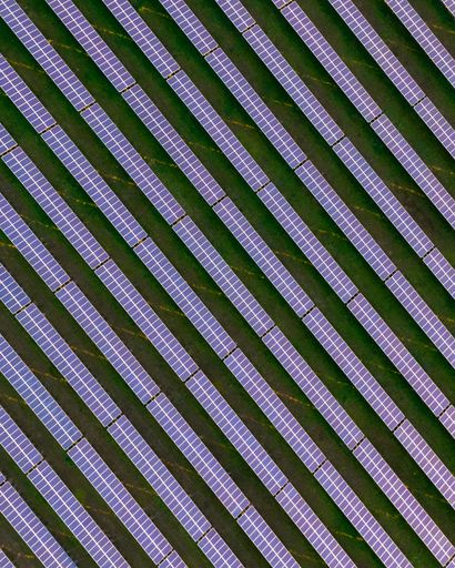 A vertical aerial shot of solar pannels in a field