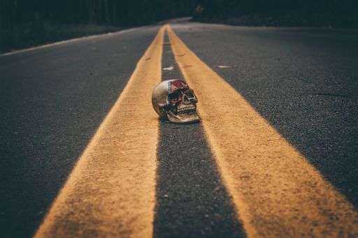 A painted human skull in the middle pf an asphalt road