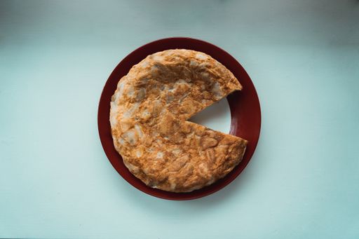 A top view of delicious Spanish omelette with a missing slice on a plate