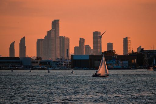 A view of downtown Toronto skyline and a yacht against an orange