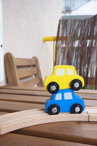A vertical selective focus shot of yellow and blue cars placed on each other on a wooden table