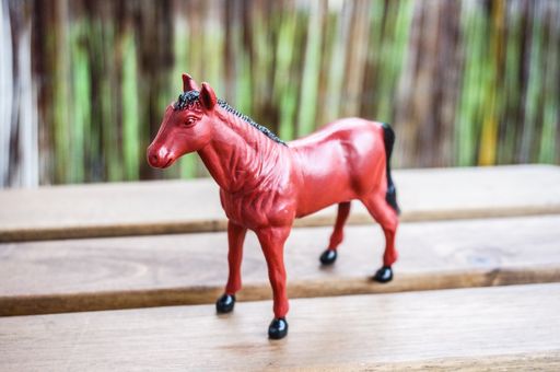 A selective focus shot of a miniature toy red rose on a wooden table