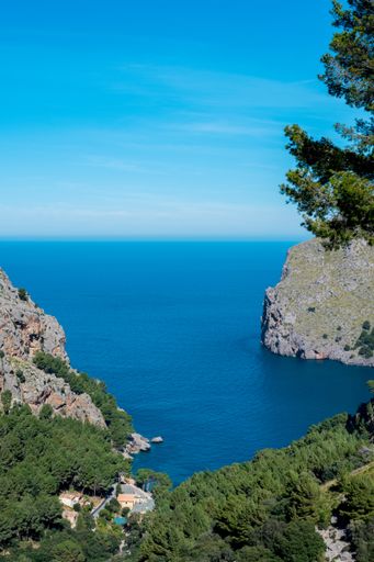 A vertical shot of a small bay in an island under a clear blue sky