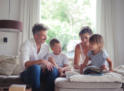 A family, including the parents and children, reading books on the bed