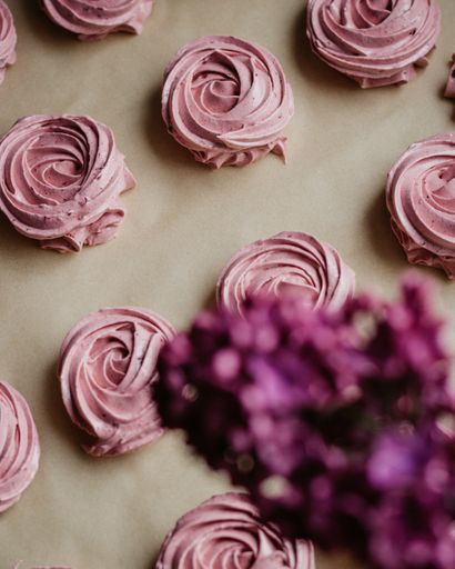 A vertical overhead shot of tasty pink desserts on a surface with lavender on the foreground