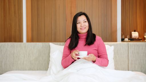 Beauty Asian women are resting in bed and drinking coffee in the morning vacation time.