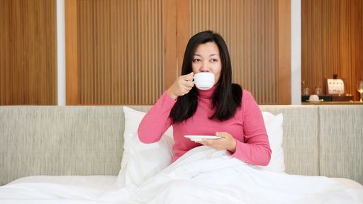 Beauty Asian women are resting in bed and drinking coffee in the morning vacation time.