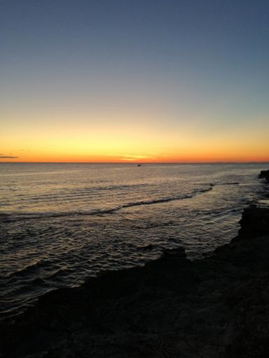 A vertical shot of a beach surrounded by the sea during a beautiful sunset in the evening - nice for wallpapers