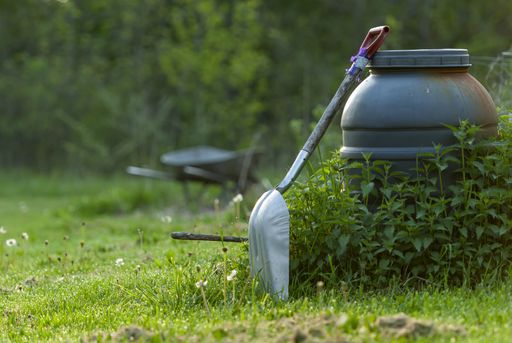 A closeup shot of a shovel in the garden with trees on the background