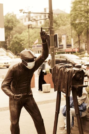 A vertical shot of a cameraman and a camera statue in a park during the day