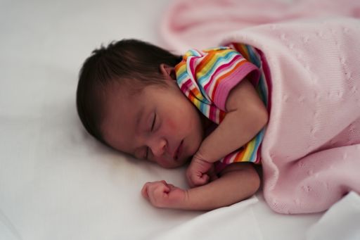 A high angle shot of a baby girl sleeping peacefully on the bed