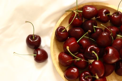 A high angle shot of a wooden bowl full of fresh cherries