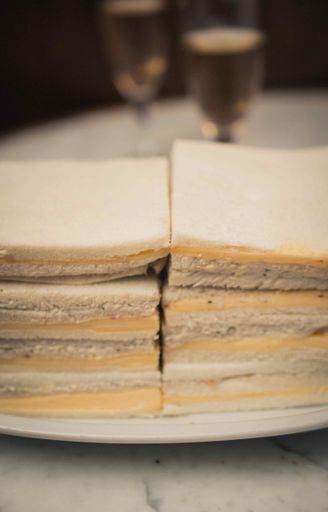 A vertical shot of cheese toast sandwiches on a white plate on a marble table