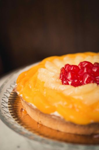 A vertical shot of a biscuit cake with cherries on top on a marble table