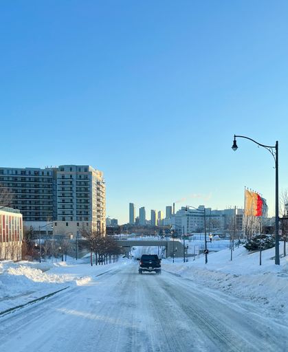 A vertical shot of a car driving on a road covered in snow in Canada