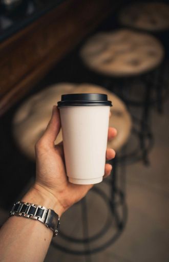 A vertical high angle shot of a male holding a white takeaway cup