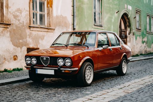 The Alfa Romeo Alfetta GT GTV parked in front of old buildings on a street in Znojmo, Czech Republic