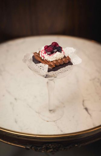 A vertical shot of a chocolate dessert with berries on top in a glass plate