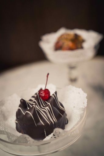 A vertical shot of a chocolate dessert with a cherry on top in a glass plate