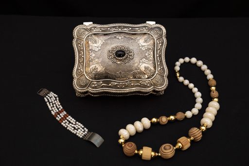 A closeup shot of silver jewelry box and a necklace and bracelet isolated on black background