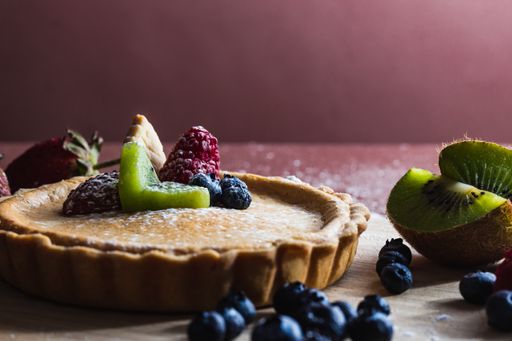 A closeup shot of treacle tart with blueberry, raspberry, strawberry and kiwi