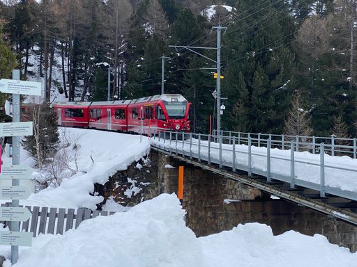 A red train goes over the bridge in winter