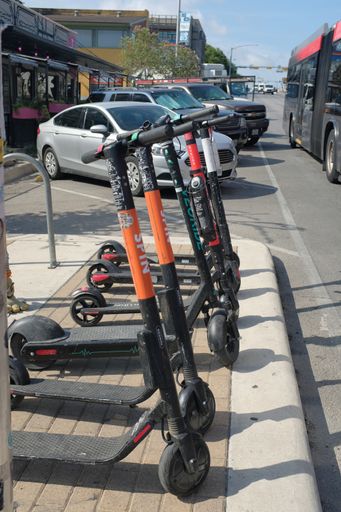 A vertical shot of parked scooters on the sidewalk