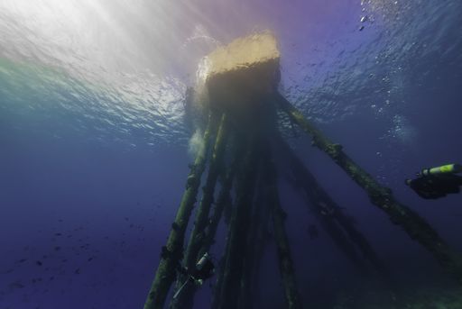 An underwater view of a saltwater pier with scuba divers swimming