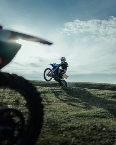 A photo of a man jumping with a motocross bike in nature