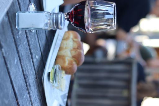 A vertical shot of the bun with sauces and a glass of wine on the table in the open-air restaurant