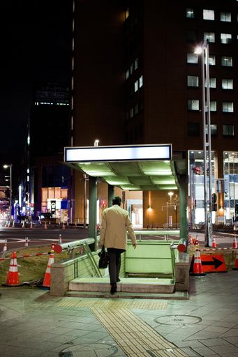 A rear view of a male going down to the subway in the city late in the evening
