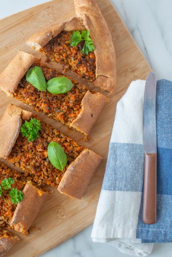 A vertical top view of a sliced Turkish pide on a wooden tray