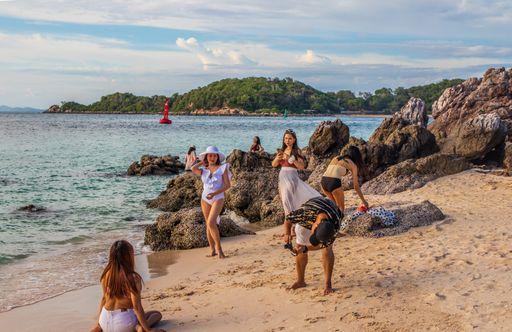 A photoshoot or session on a beach and in the sea with several models and a photographer