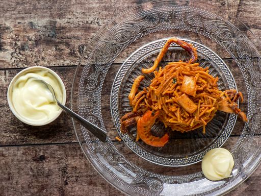 A top view of noodle paella a typical Catalan dish made with noodles and seafood with garlic sauce and oil on a glass plate