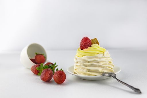 A cream muffin with strawberry and cracker isolated on a blurred background