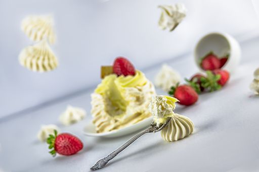 A cream muffin with strawberry and cracker isolated on a blurred background