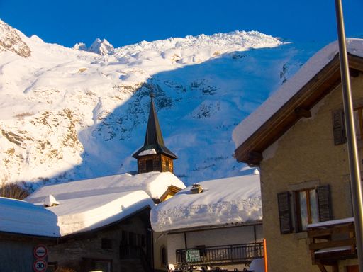 A beautiful landscape of snow trees, old houses on snow ground in French  Haute-Savoie with a blue sky