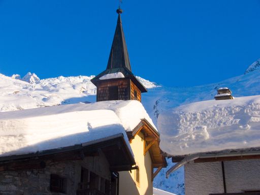 A beautiful landscape of snow trees, old houses on snow ground in French  Haute-Savoie with a blue sky