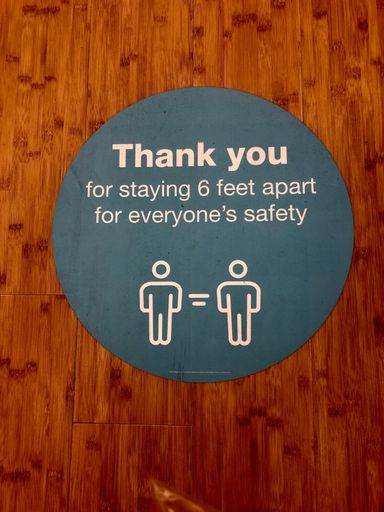 A vertical shot of a sign advocating people to keep social distancing measures