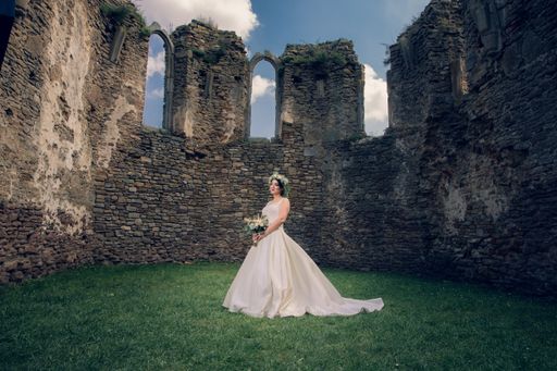 A caucasian bride wearing a white wedding dress while posing in a park